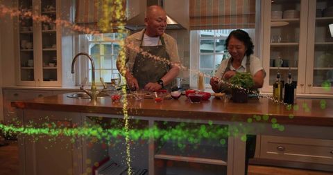 Mature couple cooking together in cozy kitchen chopping basil and preparing dinner