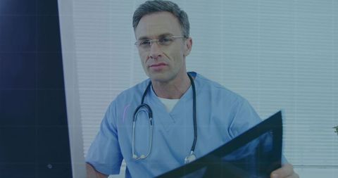 Experienced physician examining x-ray on monitor in modern clinic with stethoscope