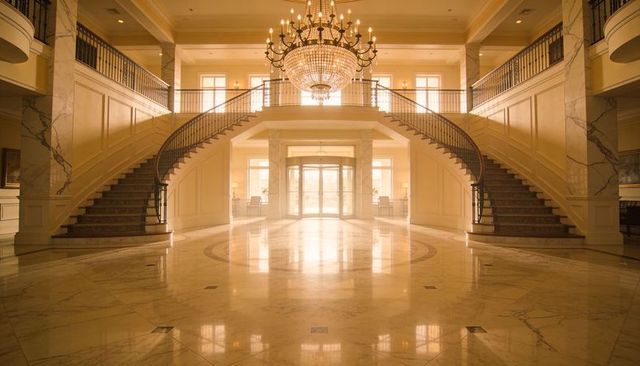 Grand luxury hotel foyer with twin curved staircases, crystal chandelier, marble atrium
