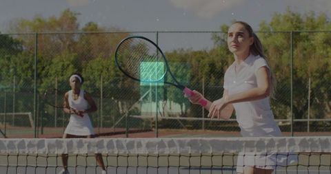 Women playing competitive tennis with active focus outdoors