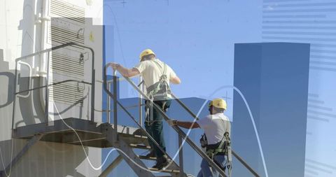 Two technicians climbing rooftop metal staircase wearing helmets, fall protection harnesses