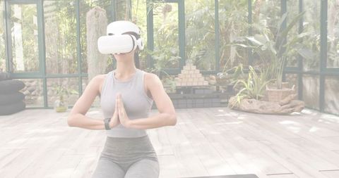 Midadult Woman Meditating with VR Headset on Yoga Mat in Sunlit Conservatory for Wellness