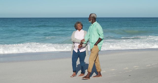 Happy african american senior couple holding hands on beach by seaside with copy space. Retirement, lifestyle, vacation, summer, happiness, wellbeing concept, unaltered.
