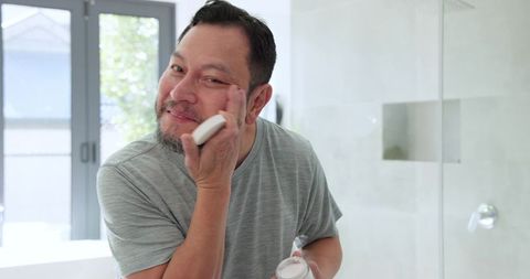 Senior man practicing skincare routine in modern bathroom