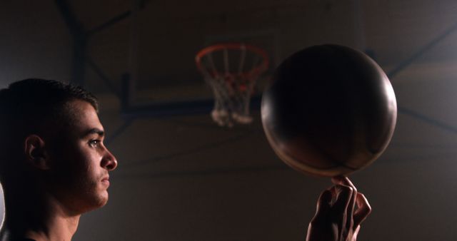 Young Man Spinning Basketball on Finger in Dimly Lit Gym - Download Free Stock Images Pikwizard.com