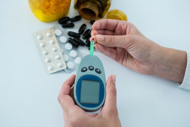 Visual focuses on man testing blood sugar levels with glucometer. Scene includes various medications and pills on table. Useful for illustrating diabetes management, healthcare practices, medical equipment usage, and patient monitoring.
