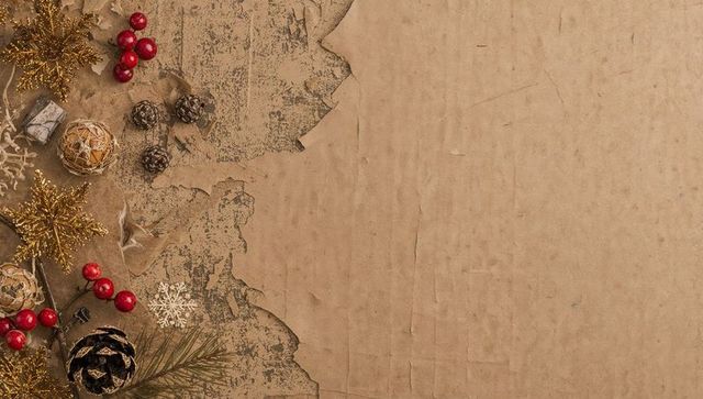 Rustic holiday flatlay torn kraft paper gold glitter stars red berries pine cones with copy space