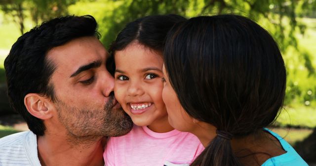 Smiling girl being kissed by his parents in park - Download Free Stock Photos Pikwizard.com