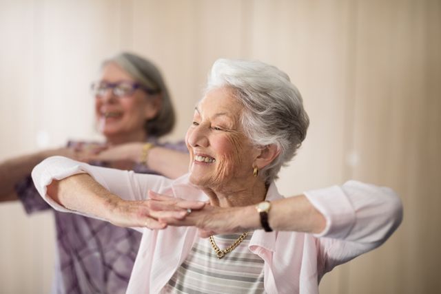 Senior women engaging in light exercise at a retirement home, promoting active and healthy lifestyles. Ideal for use in health and wellness campaigns, senior living advertisements, and community engagement materials.
