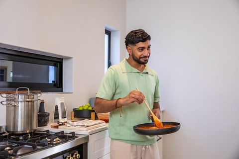 Man cooking tomato sauce modern kitchen enjoying culinary activity