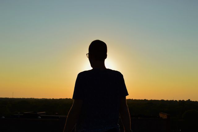 Man Silhouetted by Sunset, Enjoying Peaceful Evening - Download Free Stock Photos Pikwizard.com