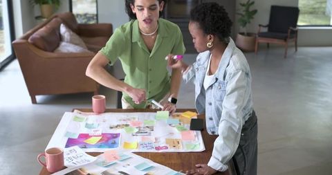 Diverse Creative Duo Brainstorming with Sticky Notes on Table in Bright Airy Studio