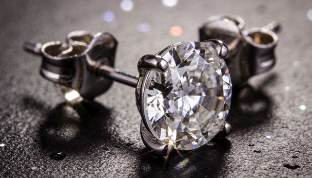 Sparkling round brilliant diamond stud catching light macro with water droplets and bokeh