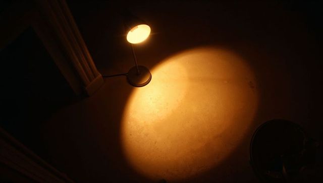 Adjustable Desk Lamp Casting Warm Circular Glow on Textured Concrete Floor