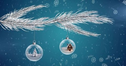 Hanging glass baubles with snowy cabin and miniature tree on frosty silver pine branch