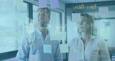 Colleagues discussing ideas behind transparent glass in modern office