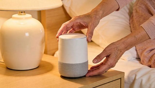 Senior placing smart speaker on nightstand beside lamp, bedside comfort and tech care