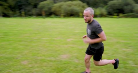 Man Jogging Energetically on Lush Green Field in Nature