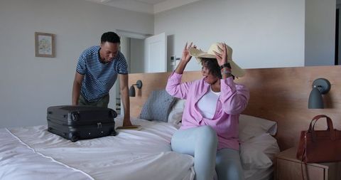 Couple packing suitcase on bed for vacation preparation