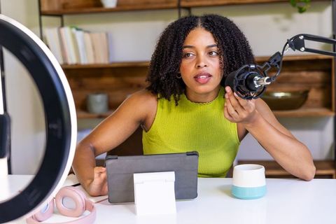 African american woman podcasting in home studio with ring light, microphone, tablet