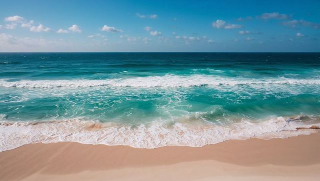 Turquoise Waves Rolling onto Golden Sandy Shoreline under Clear Blue Sky