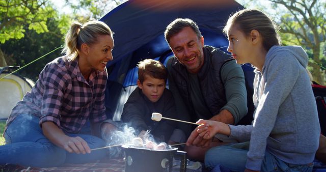 Family enjoying quality time on a camping trip in nature. Perfect for outdoor activity promotions, family bonding concepts, summer travel, adventure blogs, or products related to camping gear and outdoor activities.