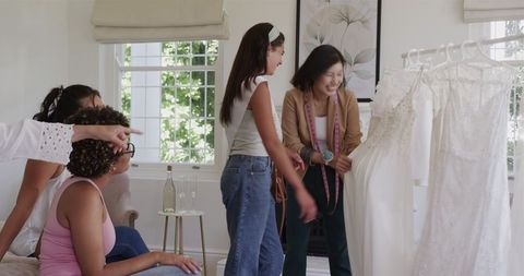 Bride-to-be choosing wedding dress with friends excitedly