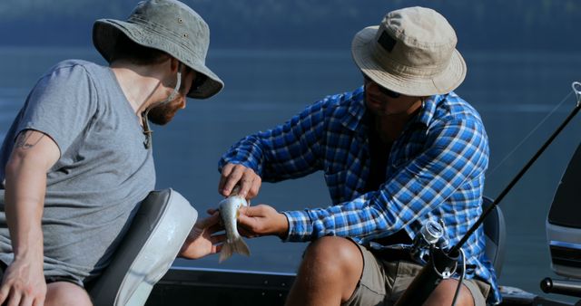 Two middle-aged men, one Caucasian and one Asian, are enjoying a day of fishing, with copy space. They appear to be in a conversation about the fish one of them has just caught.