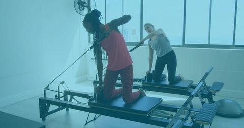Women practicing pilates with reformers in sunlit studio