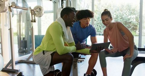 Personal trainer coaching young couple at modern gym