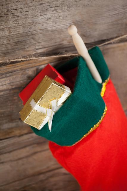 Christmas stocking with a gift box hanging on a wooden wall. Ideal for holiday-themed promotions, festive greeting cards, seasonal advertisements, and Christmas decor inspiration.