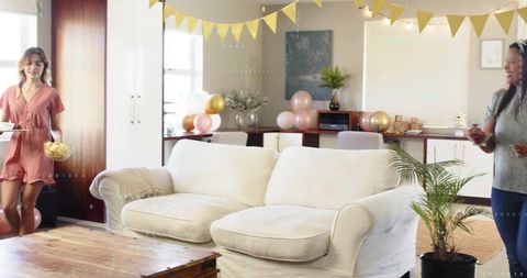 Cozy cream sofa in open-plan living room with friends gathering and pastel party decor