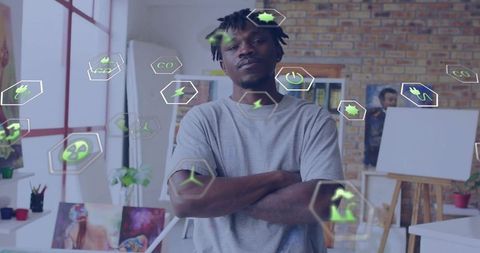 Confident artist standing with arms crossed in art studio with green energy icons overlay