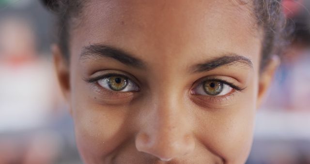 This image captures a close-up of a young girl's face focusing on her striking green eyes and a subtle smile. Perfect for use in advertising campaigns, educational settings, parenting articles, or websites promoting children's fashion and beauty.