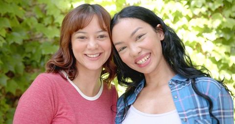 Smiling Young Female Friends Outdoors Under Sunny Foliage