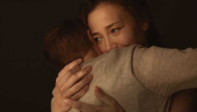 Mother embracing young child, tender hug highlighting knit sweater and warm glow