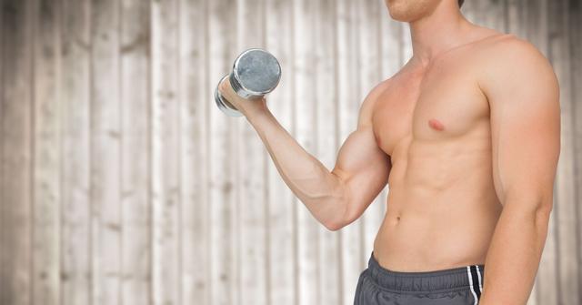 Muscular man lifting dumbbell against wooden wall background. Ideal for use in fitness, workout, and strength training concepts. Can be used for promoting gym memberships, exercise routines, and personal training programs.