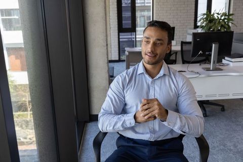 Asian Businessman in Modern Office, Relaxed and Reflective