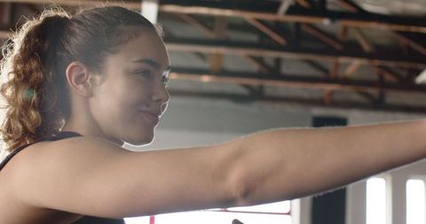 Female athlete punching forward in industrial boxing gym