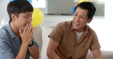 Father and Teenage Son Laughing Together in Cozy Living Room
