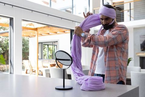 Mid Adult Man Tying Lilac Turban in Modern Kitchen