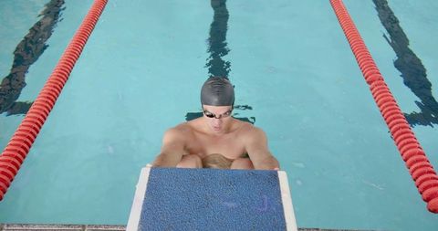 Competitive Swimmer Preparing for Race on Starting Block