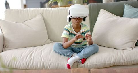 Young boy exploring virtual reality on comfortable sofa