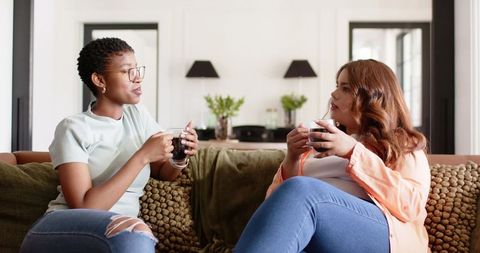 African american friends sharing coffee and conversation on cozy living room sofa