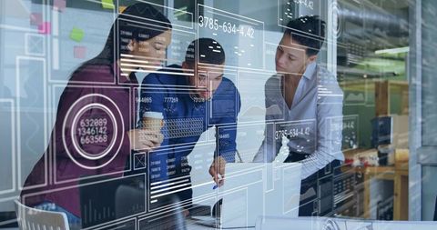 Team collaborating over laptop with interactive data dashboard overlay in modern office meeting