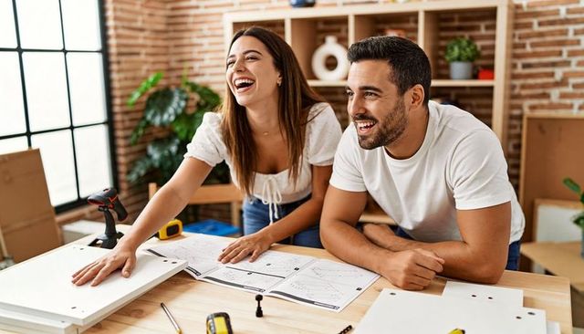 Laughing couple assembling furniture in modern loft diy renovation and home makeover