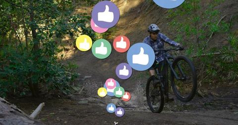 Man Performing Mountain Bike Wheelie on Forest Trail with Thumbs-Up Icons