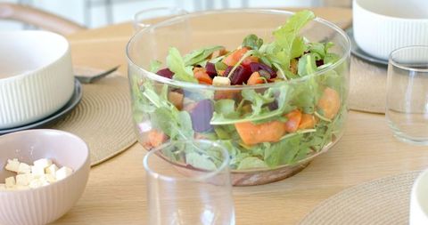 Verdant arugula and roasted beetroot salad in clear glass bowl on wooden dining table