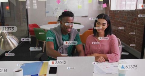 Diverse young professionals collaborating at laptop in modern glass-walled office