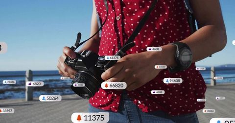 Photographer adjusting dslr with floating social media icons on boardwalk